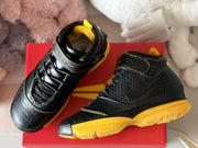 Pair of black and yellow high-top sneakers shown on a red shoebox.