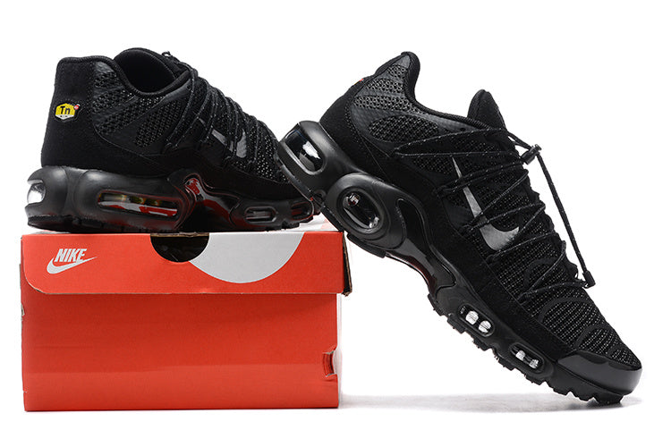 Pair of black Nike Air Max Plus-style sneakers displayed on a red shoebox