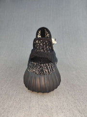 Rear view of a black sneaker showing the heel pull tab, textured upper, and ribbed dark outsole.