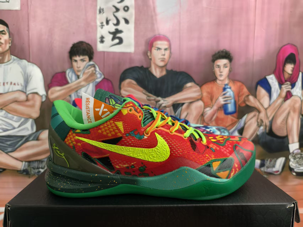 Side view of a mismatched pair of colorful Nike basketball sneakers on a black box, showing a red and green shoe with a bright swoosh and patterned upper.