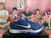 Side view showing the blue textured upper, white Swoosh, red number 8, and white midsole