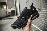 Angled view of a black and gold Nike TN-11 sneaker