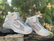 Pair of gray and off-white Nike basketball sneakers displayed on a stone surface.