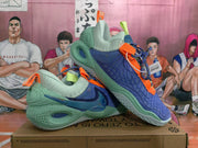 Angled view of the pair showing the layered green outsole, blue upper, orange trim, and side branding.