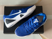 Top-down view of a pair of royal blue sneakers with white swooshes and Kobe-themed tongue markings.