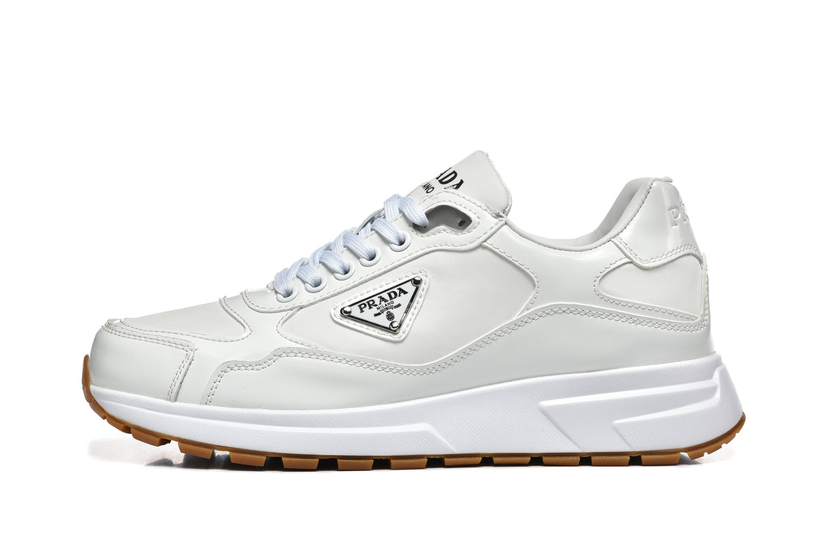 Side view of a white Prada logo sneaker with a chunky white sole and gum-colored tread.