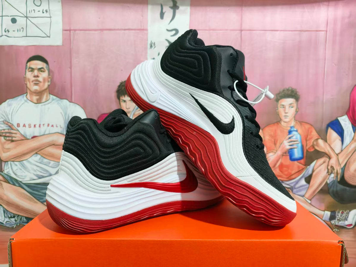 Pair of black, white, and red Nike basketball-style sneakers displayed on an orange shoebox.