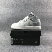 Side view of a sneaker displayed on its box; the box shows Air Jordan 1 Mid GS, color Light Bone/Grey Fog, style code 554725 053, and size 5.5Y.