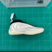 Top-side view of the sneaker placed on a green cutting mat, showing the black upper and silver side panel.