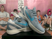 Angled view of the paired grey and blue basketball sneakers with visible Caitlin graphics and textured uppers.