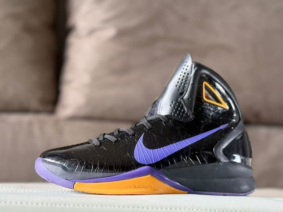 Side view of a black Nike high-top basketball shoe with a purple Swoosh and gold midsole accent