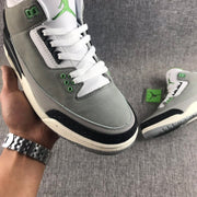 Close-up side view showing the gray upper, white laces, green eyelets, and black textured toe overlay.