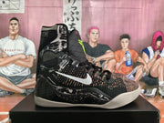 Side view of black high-top Nike basketball sneakers with multicolor woven panels, white Swoosh branding, graphic side details, and a light-colored outsole.