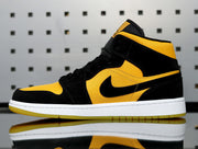 Side profile of a yellow and black Jordan high-top sneaker showing the black side branding, white midsole, and yellow outsole.