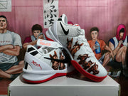 Three-quarter view displaying black Swoosh branding, horse illustrations, white uppers, and red outsoles.