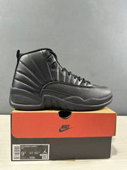 Black Jordan Air Jordan 12 high-top sneaker displayed on its shoebox; the box label shows EU 43, US Men 9.5, UK 8.5, and CM 27.5.