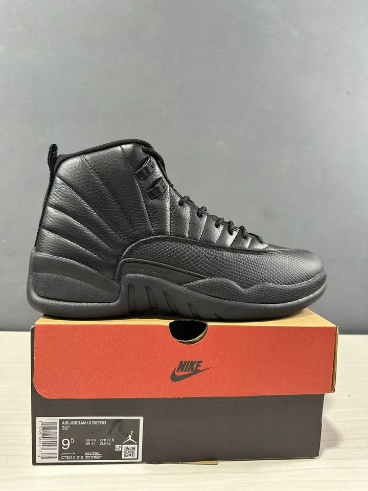 Black Jordan Air Jordan 12 high-top sneaker displayed on its shoebox; the box label shows EU 43, US Men 9.5, UK 8.5, and CM 27.5.