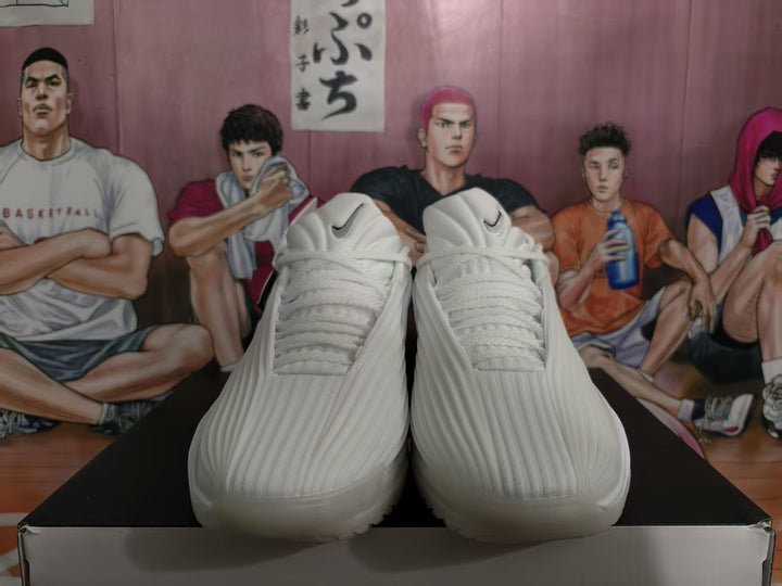 Front view of white Nike basketball sneakers with black Swoosh details displayed on a shoebox.