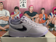 Side view of a purple and gray sneaker with a dark swoosh-shaped side detail and textured upper panels.