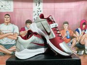 Pair of grey, white, and burgundy Nike basketball sneakers displayed on a box, showing the side Swoosh and layered upper design.