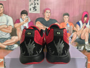 Rear view of red and black basketball sneakers showing black heel panels, gray graphics, and red outsole edges.