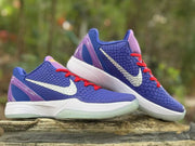 Pair of purple and blue Kobe 6 sneakers positioned together outdoors, highlighting the red laces and white midsoles.