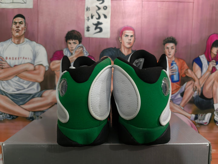 Rear view of white and green high-top basketball sneakers with black collars and outsole accents, displayed on a box.