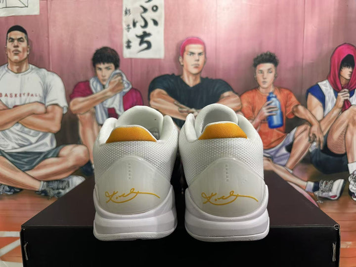 Rear view of white Nike Kobe basketball shoes showing gold heel accents.