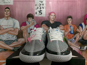 Front view of black-and-white Converse sneakers with white laces, pink accents, and white textured soles.