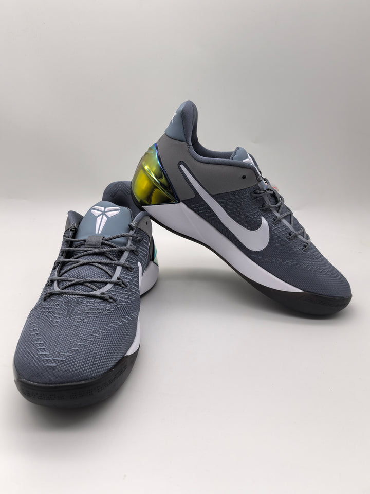 Pair of cool grey Nike basketball sneakers shown from the front and side, with white side branding and translucent yellow-green heel details.
