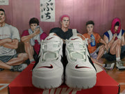 Front view of white and black Nike sneakers with white laces and red-accented branding.