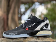 Side view of a black Kobe 6 sneaker with white laces, textured upper, glossy black overlays, white heel panel, and translucent sole.