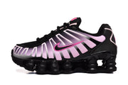 Side profile of a black Nike Shox TL sneaker with pale pink panels and bright pink accents.