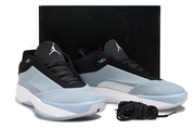Pair of blue-gray, black, and white Jordan 40 shoes with a black box in the background.