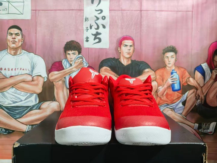 Pair of red and white Nike basketball sneakers viewed from the front on a black shoebox.