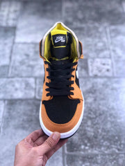 Top-down view showing the black perforated toe box, orange toe overlay, black laces, and yellow tongue lining.