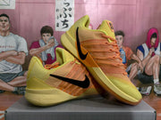 Angled side view highlighting the black Swoosh, orange upper details, and yellow sole.