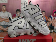 Angled side view of the white and black sneakers highlighting the AIR lettering, lace loops, perforations and outsole structure.