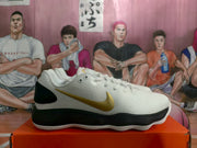 Side view of a white low-top sneaker with a metallic gold swoosh, black heel panel, black midsole, and white outsole.