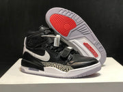 Angled view of the sneakers with one outsole facing upward, showing circular red traction details and molded tread.
