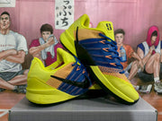 Angled display of the yellow and blue Nike sneakers, highlighting the black Swoosh, blue laces, and layered upper.