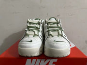 Front view of white Nike sneakers with green laces and small toe logos