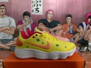 Side view of the yellow sneaker with colored spots, a contrasting side mark, red collar trim, and textured white sole.