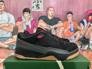 Side view of one black and dark green Jordan sneaker with red branding, textured side panel, and gum-colored outsole.