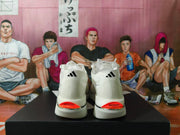 Rear view of white adidas shoes with black heel logos and red heel accents