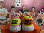 Rear view of mismatched yellow and pink Nike sneakers with contrasting heel panels and white textured outsoles.
