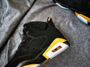 Close-up side view showing perforated black panels, gold accents, and the visible heel cushioning window.