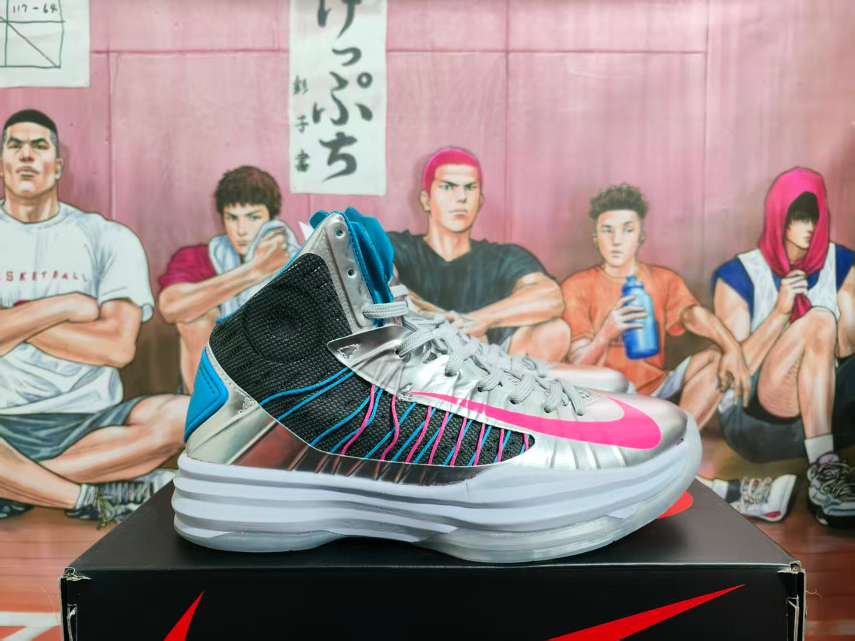 Side view of silver Nike high-top basketball sneakers with blue and pink accents on a black Nike shoebox.