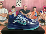 Side profile of a navy blue basketball shoe with aqua branding, skeletal-style graphics and a translucent aqua outsole.