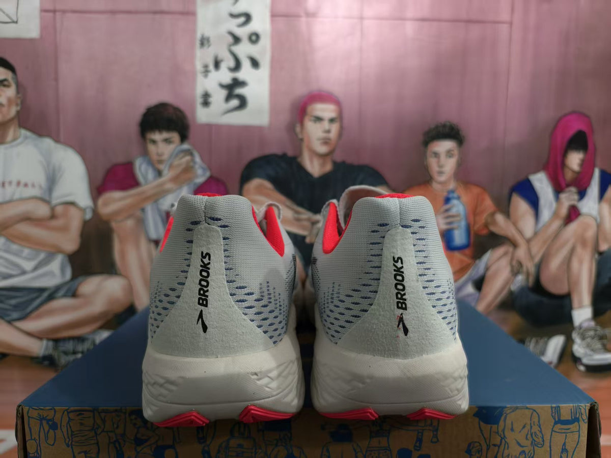 Rear view of white and gray Brooks Hyperion Max shoes with orange-red accents